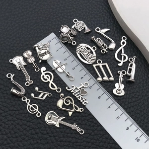 Macro view of antique silver music charms with ruler showing 1.5-3cm size scale