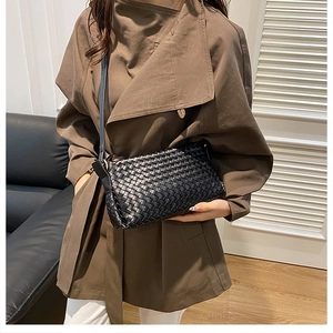 Borsa a tracolla intrecciata nera indossata da una modella in ambiente moderno