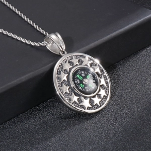 Macro shot of silver stainless steel compass pendant with star patterns on twisted chain