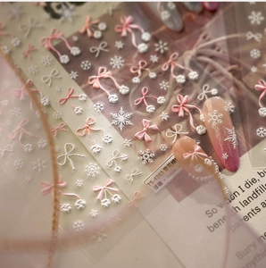 Detail of 3D embossed snowflake and bow nail stickers with soft pink texture
