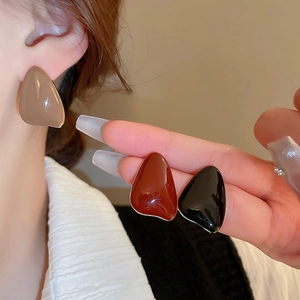 Close-up of geometric resin drop earrings in khaki, caramel, and black with gold edges