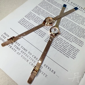 Flat lay of two rose gold mesh band quartz watches on an open fashion magazine