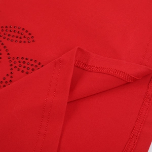 Detailed close-up of red knit dress hem with rhinestone accents and twin-needle stitching