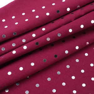 Détail du tissu en maille bordeaux avec paillettes argentées et drapé élégant