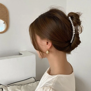 Elegant pearl hair claw clip and gold ball earrings set on a woman's side profile view