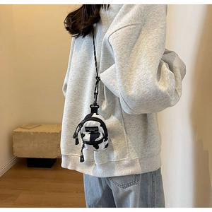 Close-up of a mini cow print crossbody bag with adjustable lanyard and branded label