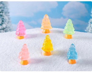 Miniature resin luminous Christmas trees in diverse colors on fake snow for DIY decor