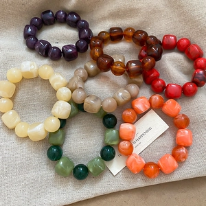 Vue à plat de bracelets en perles d'acrylique colorées à texture marbrée sur fond de jute