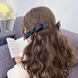 Elegant pair of black lace bow hair clips for women on brown wavy hair styling
