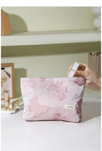Dettaglio della borsa cosmetica rosa con ricamo fiocco 3D e ampio scomparto interno