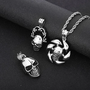 Détail de pendentifs tête de mort en acier argenté avec gravures de pirate