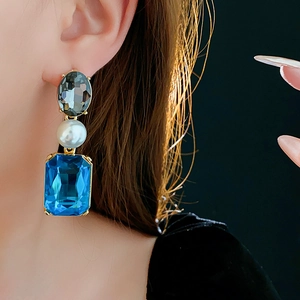 Close-up of vintage style earring with blue rectangular crystal and grey rhinestones
