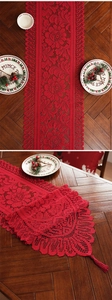 Detailed view of red festive lace table runner with elegant fringe and holiday accents