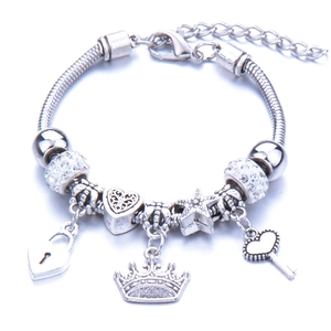 Detail view of silver bead bracelet with crown, heart lock, and star charms with crystals