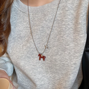 Détail du collier de style chinois avec pendentifs poney rouge et argent sur un mannequin