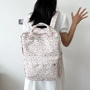 Detailed back view of a white floral canvas backpack with pink small flower pattern