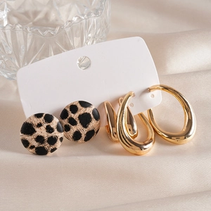 Set of leopard print button studs and gold teardrop hoop earrings on a white card