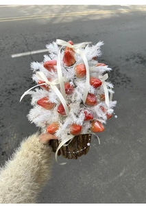 Close-up of DIY strawberry bouquet with red berries, white feathers and pearl ribbons