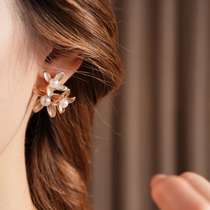 Detail of gold-plated flower earrings with white pearls on model for elegant style
