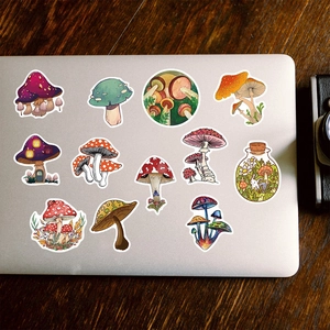 Close-up of waterproof mushroom stickers with various hand-drawn fungi designs on a laptop