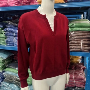 Detail of red knit sweater featuring a V-neckline with elegant white lace trim accents
