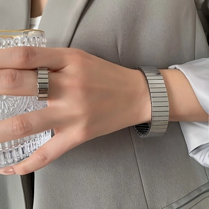 Polished silver watch strap link bracelet and ring set for men and women on a grey suit