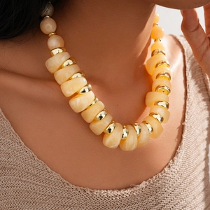 Close-up of irregular amber resin beads and gold rings on adjustable necklace