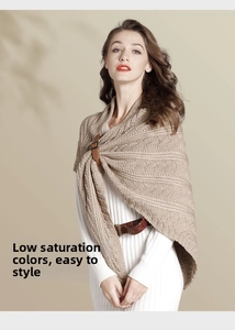 Close-up of knit shawl with brown leather buckle fastener over a white dress