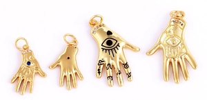 Macro shot of gold-plated Hamsa hand charms with micro-pave crystals and evil eye design