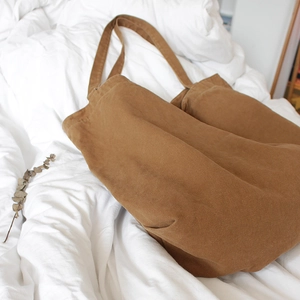 Retro brown large capacity canvas tote bag on white fabric with natural eucalyptus leaves