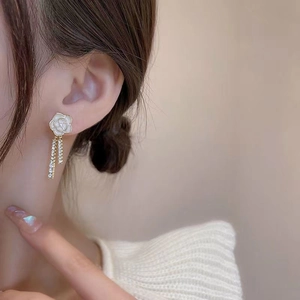 Close-up of camellia drop earrings with long sparkling diamond tassels on a model