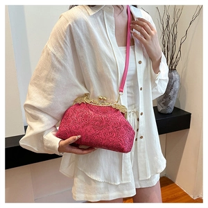 Detailed macro view of the vintage red embossed pattern and golden clasp on the shell bag