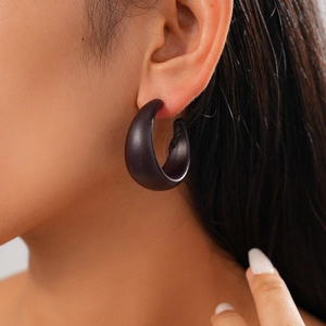 Close-up of a model wearing a thick vintage C-shaped dark brown acrylic resin hoop earring