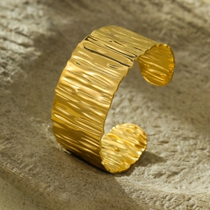 Macro view of golden stainless steel cuff bracelet with unique hammered bark texture