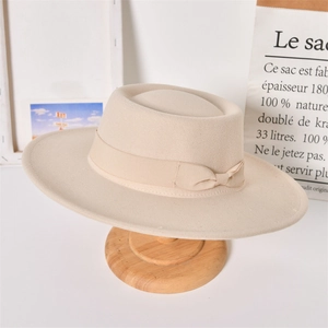 Detailed close-up of a beige wool felt fedora hat on a wooden stand with a bow detail