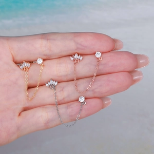 Detail of three-color chain piercing earrings with cubic zirconia held in hand