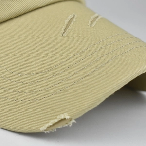 Macro shot of khaki cotton baseball cap brim with vintage distressed ripped details