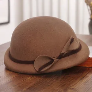 Elegant wool felt cloche hat in camel brown with ribbon bow on a wooden surface