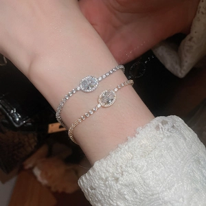 Detail of silver and rose gold bracelets with oval zircon crystals on a model wrist