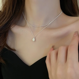 Close-up of double-layered silver pearl necklace with oval shell pendant on model