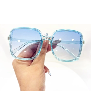 Detail shot of oversized square sunglasses with blue gradient lenses and transparent frame