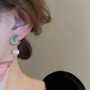Close-up of vintage moon earring with resin inlay and elegant white pearl drop pendant