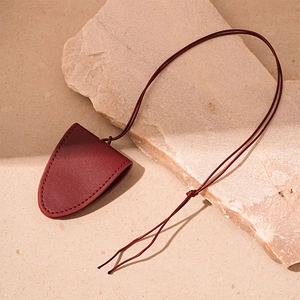 Macro view of burgundy faux leather bell-shaped pendant with fine stitching detail