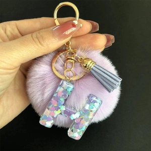 Détail du porte-clés pompon violet avec lettre H en résine et paillettes de cœur colorées
