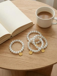 Detailed view of white cat eye stone bead bracelets with gold Fu character charms