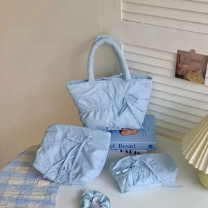 Detailed view of blue quilted cotton bag set with elegant bow knots on fabric texture