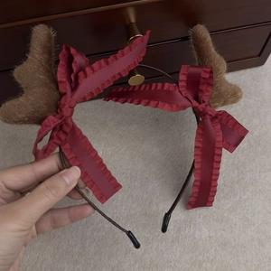 Close-up of plush brown reindeer antlers with red ribbon bows on a Christmas headband