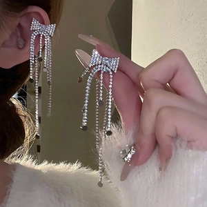 Macro detail of silver bow earrings featuring shimmering zircon tassels and clip-on design