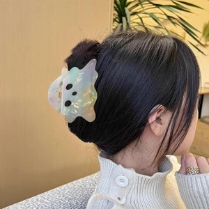 Détail d'une pince à cheveux fantôme blanc nacré portée sur une coiffure en chignon