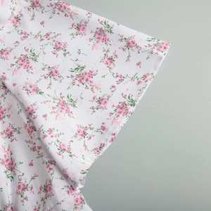 Dettaglio della stampa floreale rosa su tessuto bianco con cuciture e trama di qualità